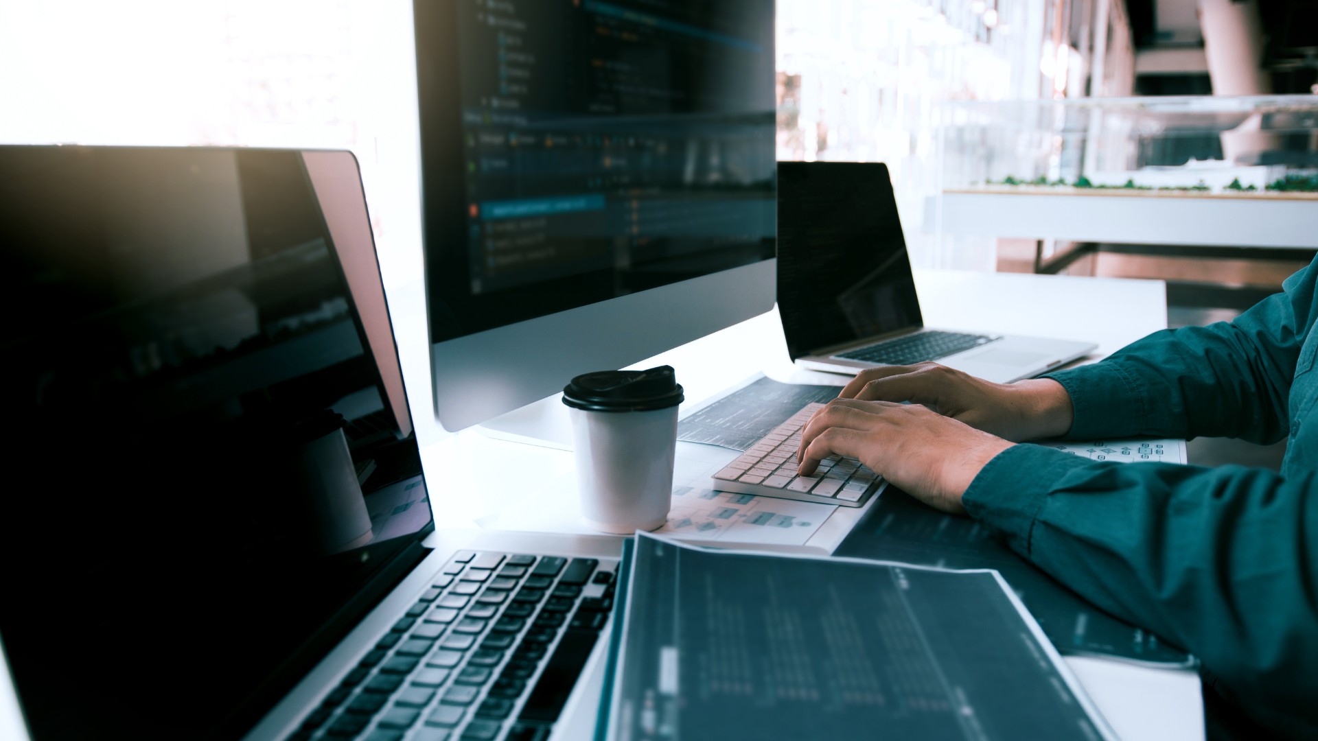 Personne utilisant plusieurs appareils informatiques dans un espace de travail.