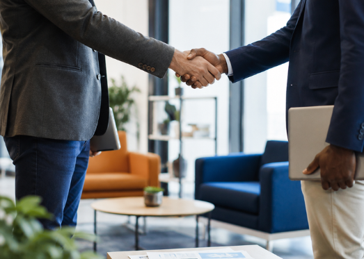 Deux professionnels se serrant la main dans un environnement de bureau moderne, symbolisant le partenariat et la confiance.